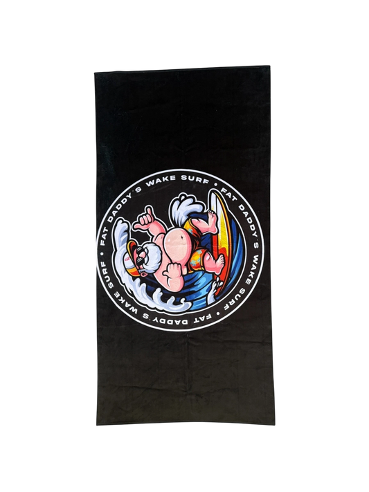 Fat Daddy's Wake Surf black quick-dry towel featuring a cartoon character surfing on a surfboard with waves.